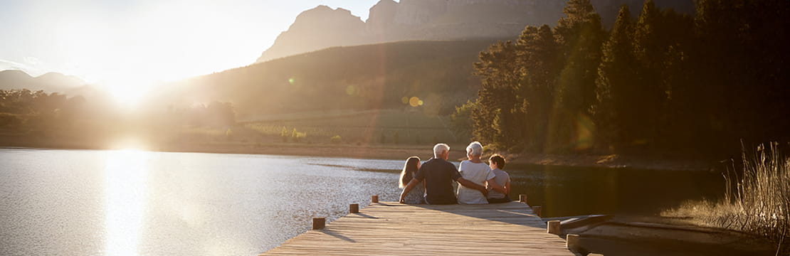 Rear View Of Family Standing On Wooden Jetty By Lake